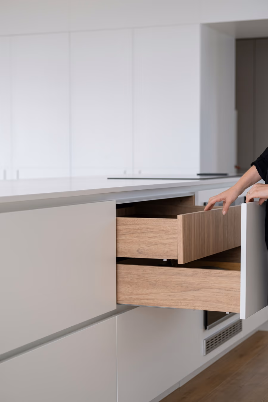 Two stacked kitchen base drawers pulled fully open on undermount runners, showing solid drawer boxes behind handleless fronts