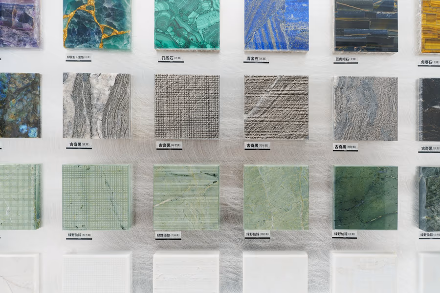 A display wall of small square stone samples in greens, greys and blues, each labelled beneath
